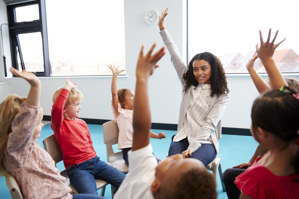 A group of children raising their hands Description automatically generated