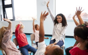 A group of children raising their hands Description automatically generated